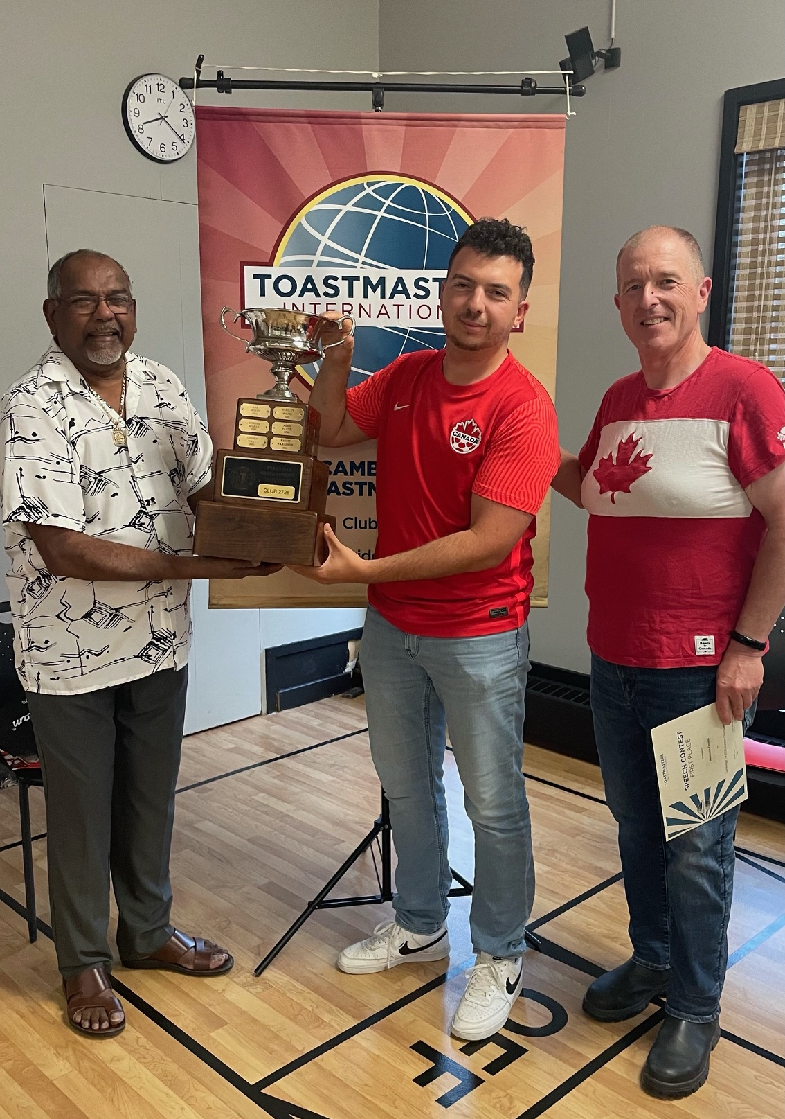 Asaad Kamaal presenting Mackenzie Ferreira with the first place trophy, accompanied by the Contest Chair, Kevin Swayze