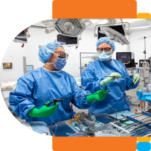 A housekeeping attendand in blue scrubs and gloves is smiling while cleaning a medical device