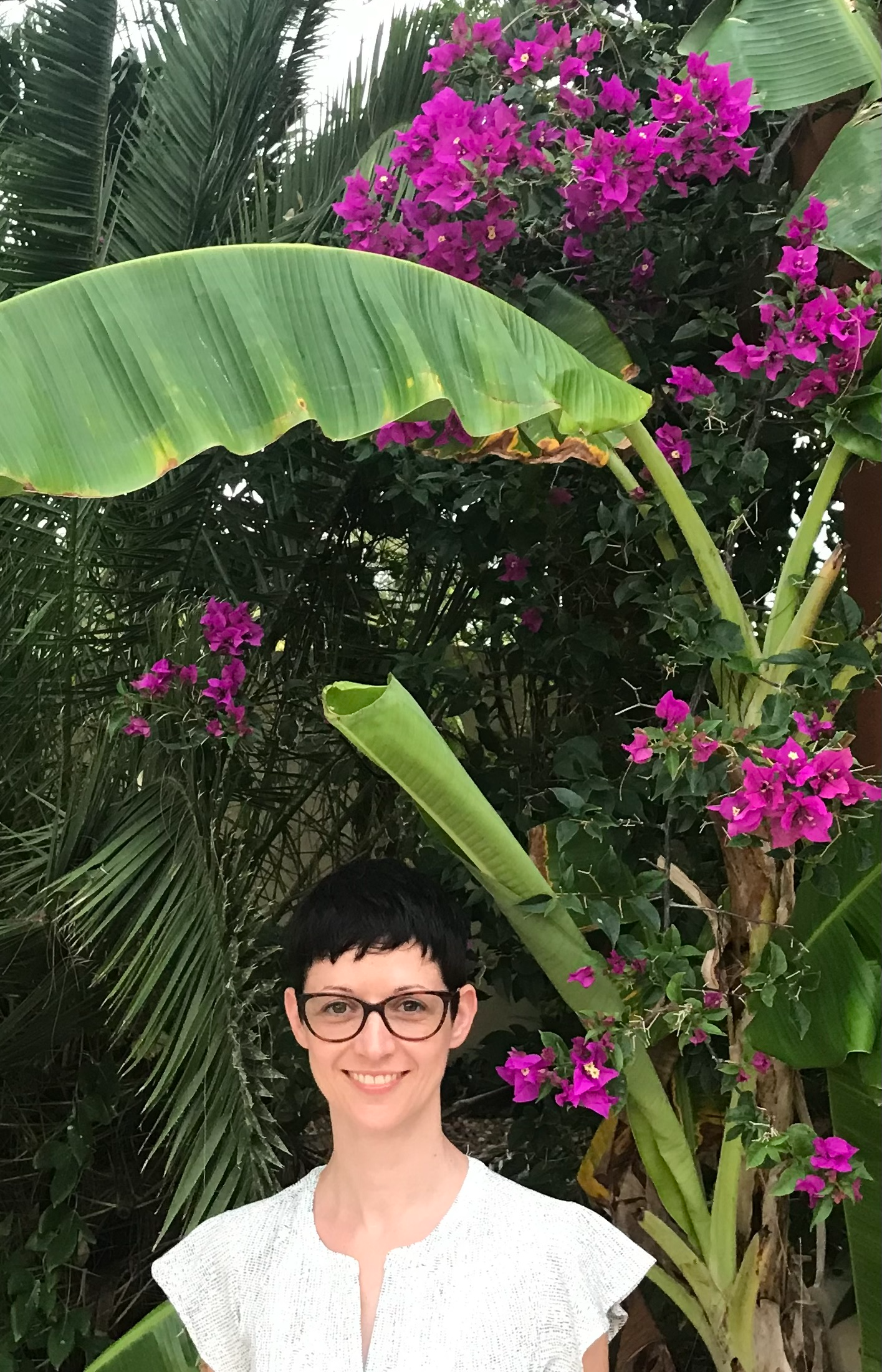 another picture of Francesca smiling, while surrounded by lush vegetation and bright purple flowers