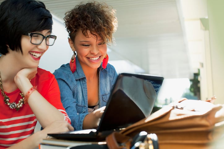 Young women smiling while using laptop together for an Italian online session