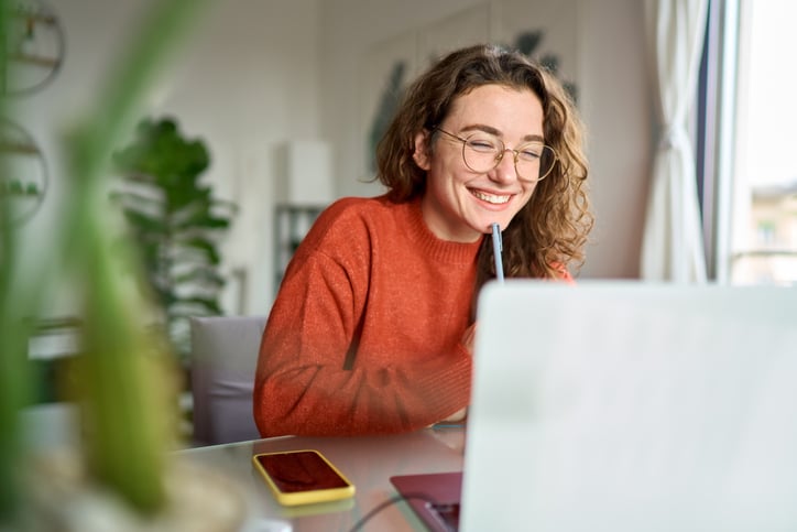 Young happy woman student using laptop at home.