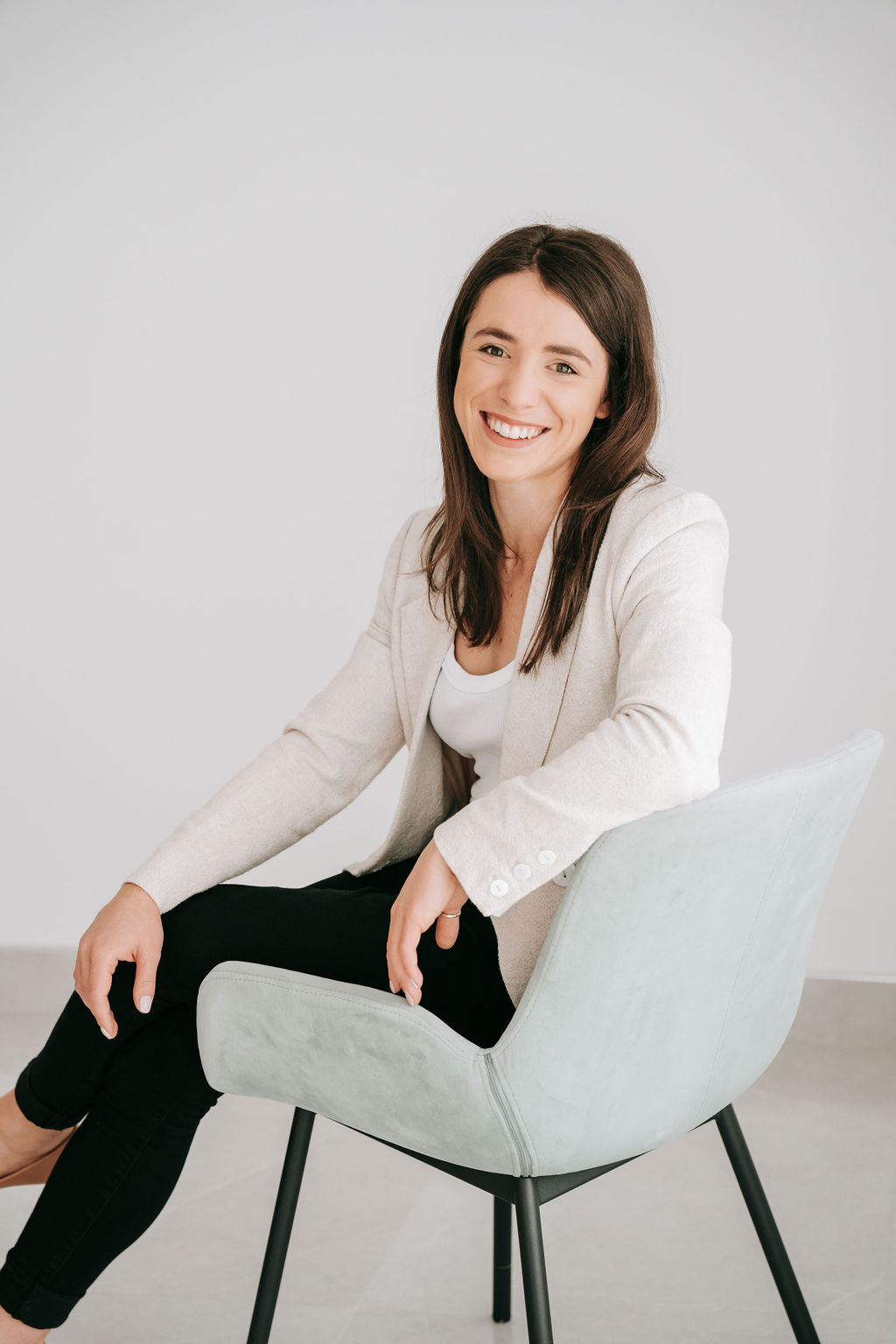 Girl with brown hair sitting on chair smiling directly at camera