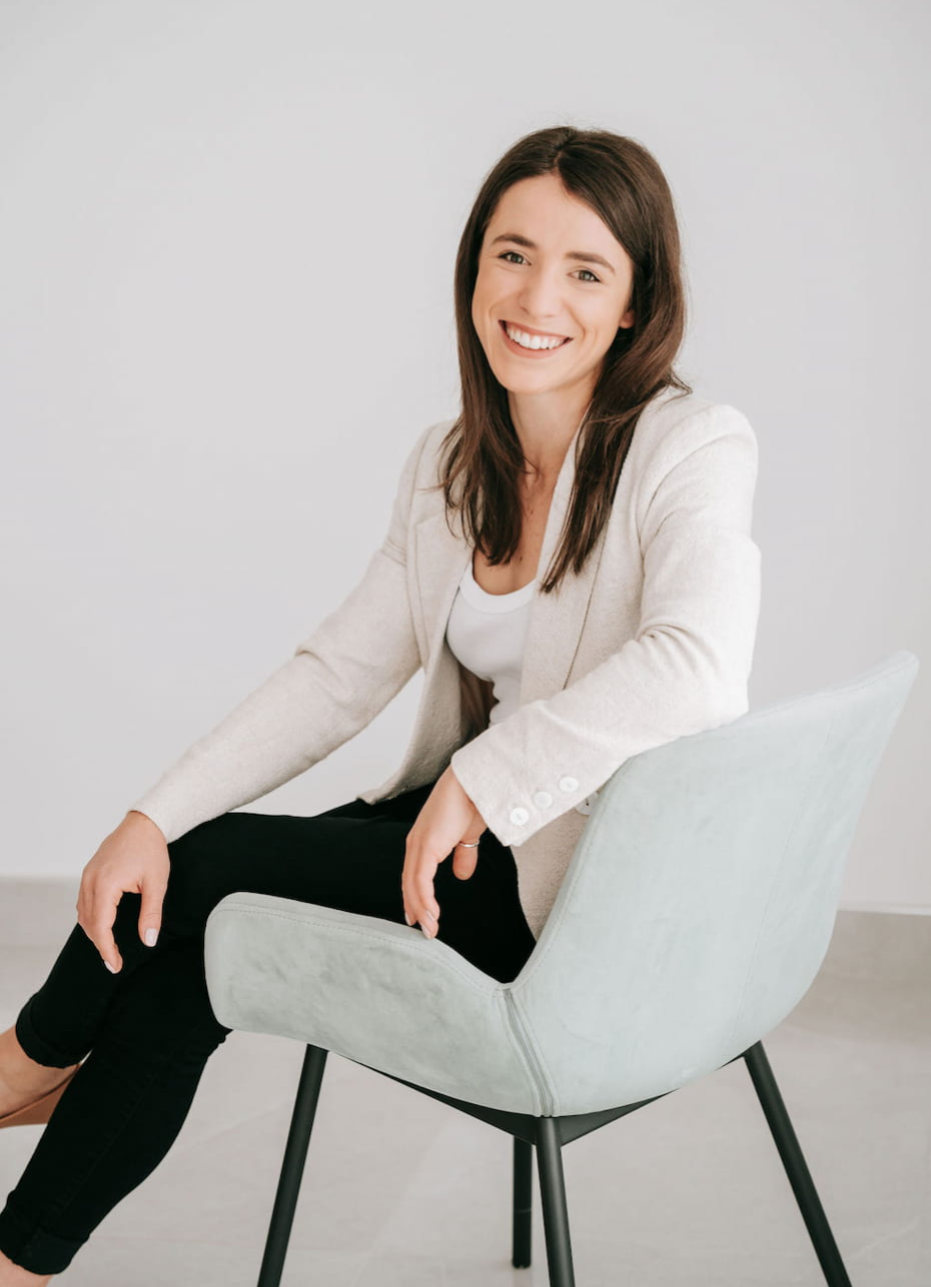 Girl with brown hair sitting on chair smiling directly at camera