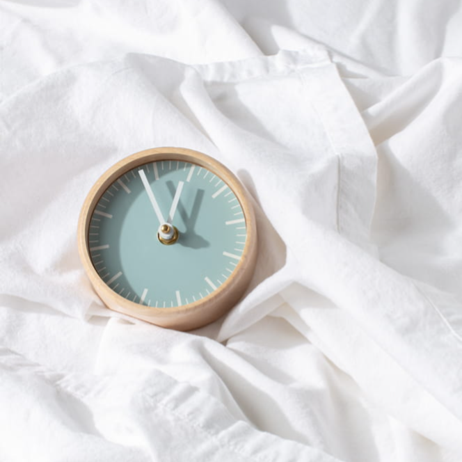 Wooden clock resting on white linen, representing calm and peace of mind