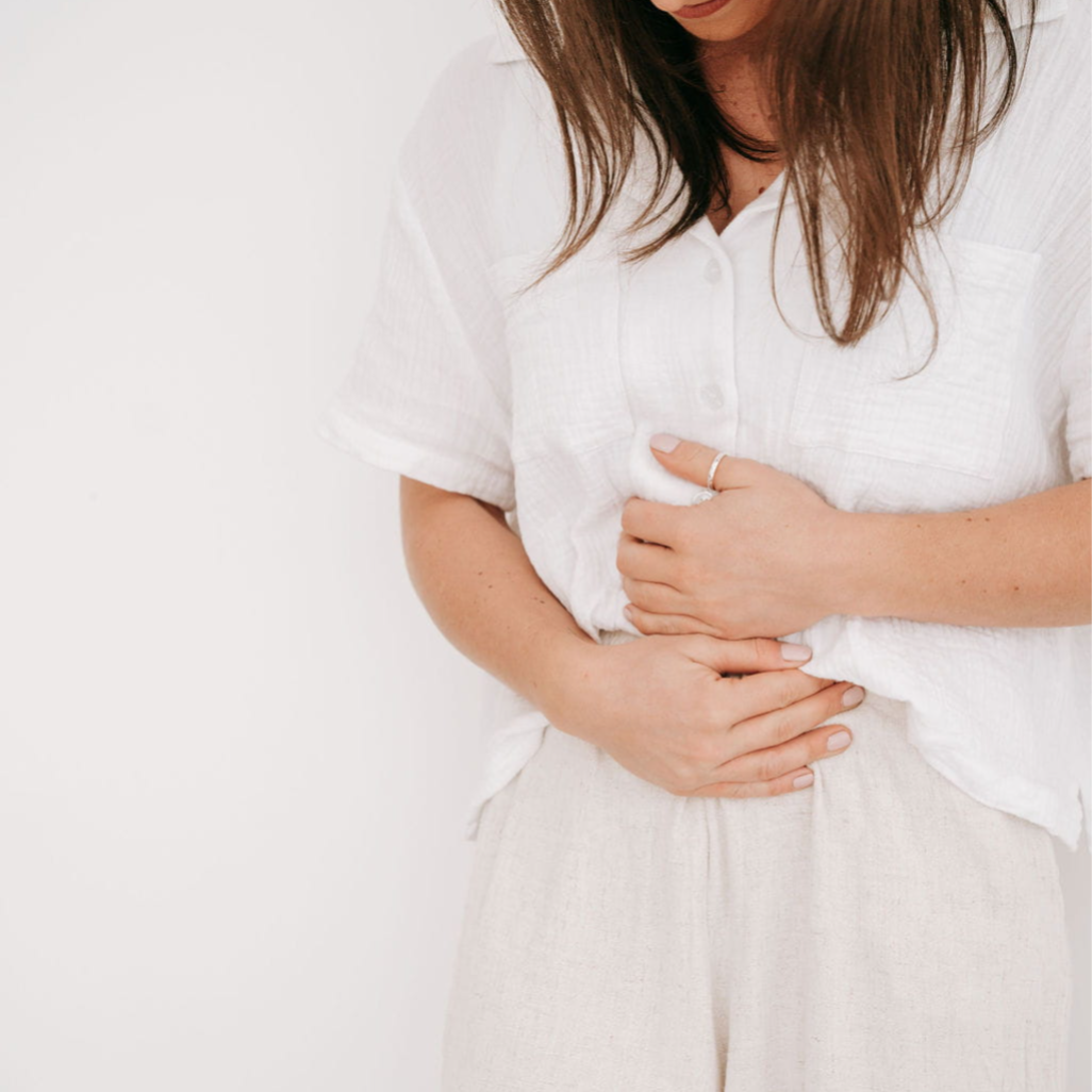 Woman holding stomach, representing gut health and IBS symptoms