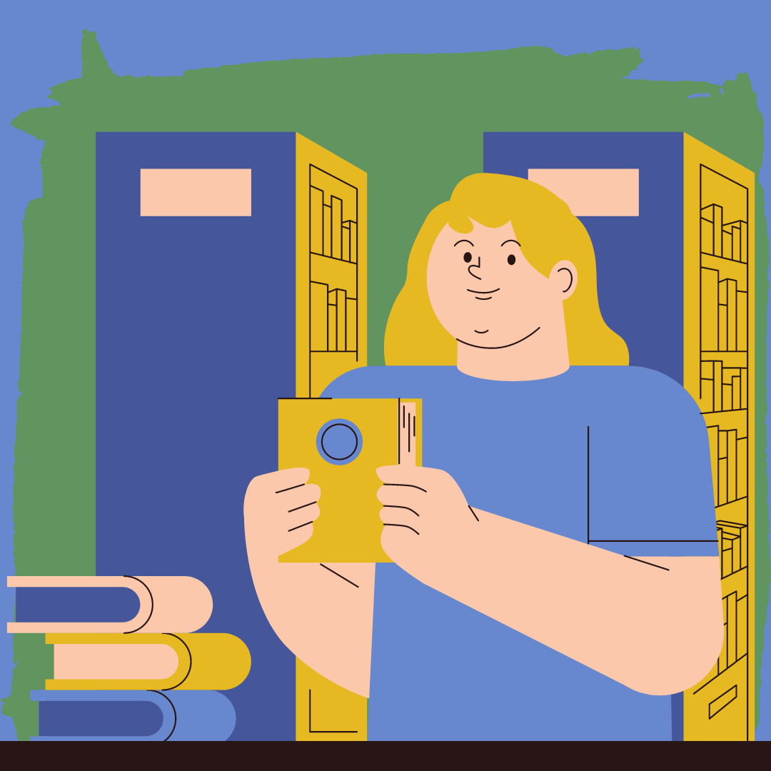 A man standing behind a library desk holding a book.