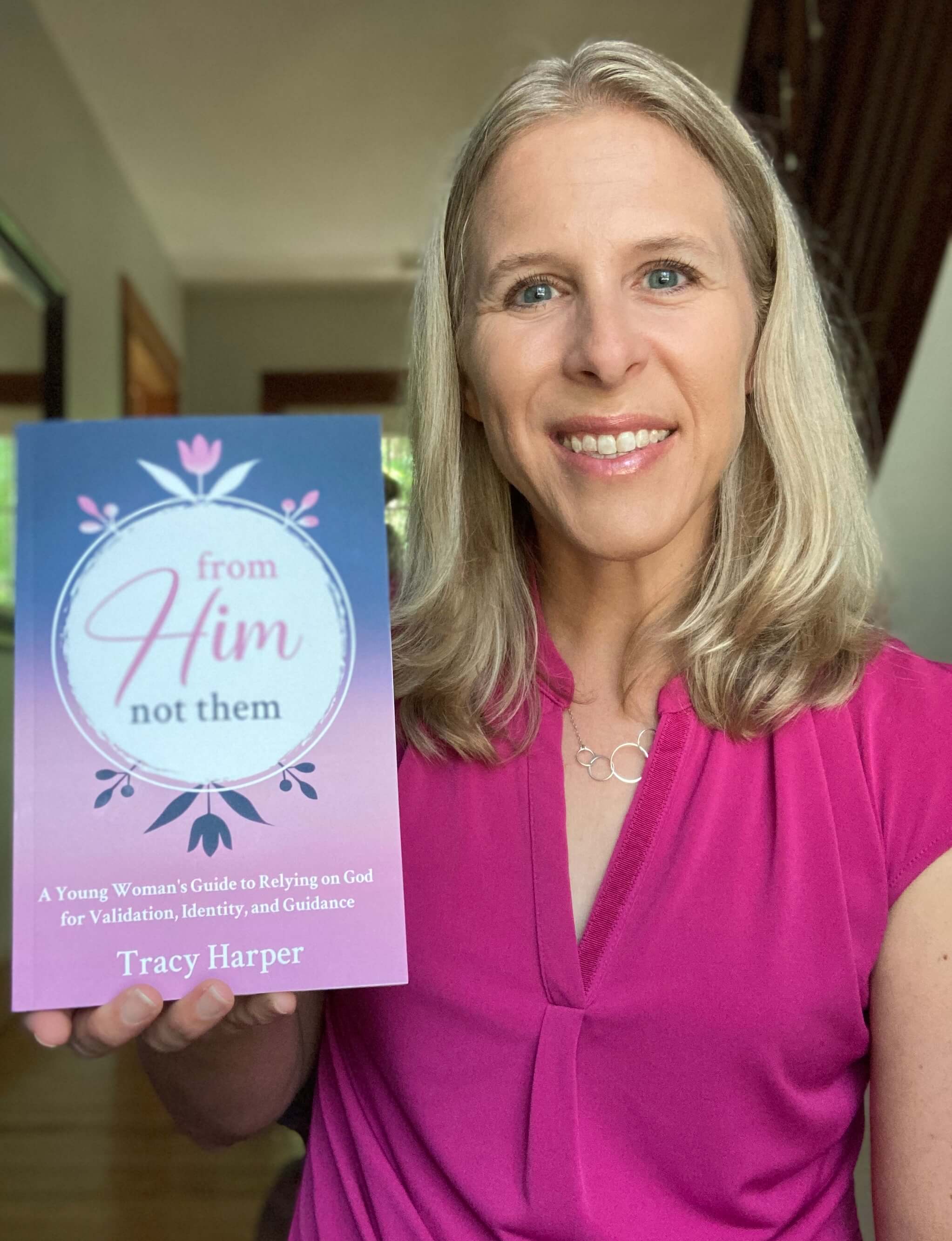 Tracy Harper holding a copy of her book From Him, Not Them