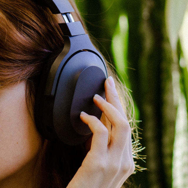 Woman holding headphones to her ear