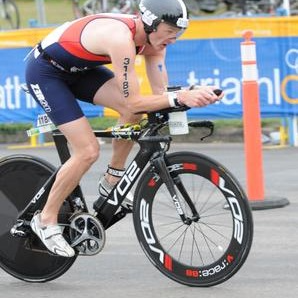 Triathlete riding a disc-wheel time-trial bike at a race