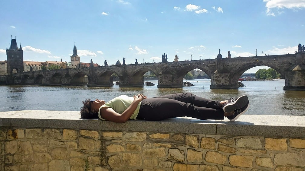 woman laying parallel to Prague's Charles Bridge