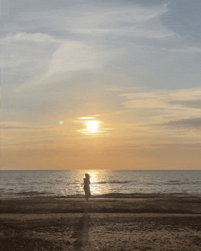 Julia running towards the ocean and opening her arms to the sun