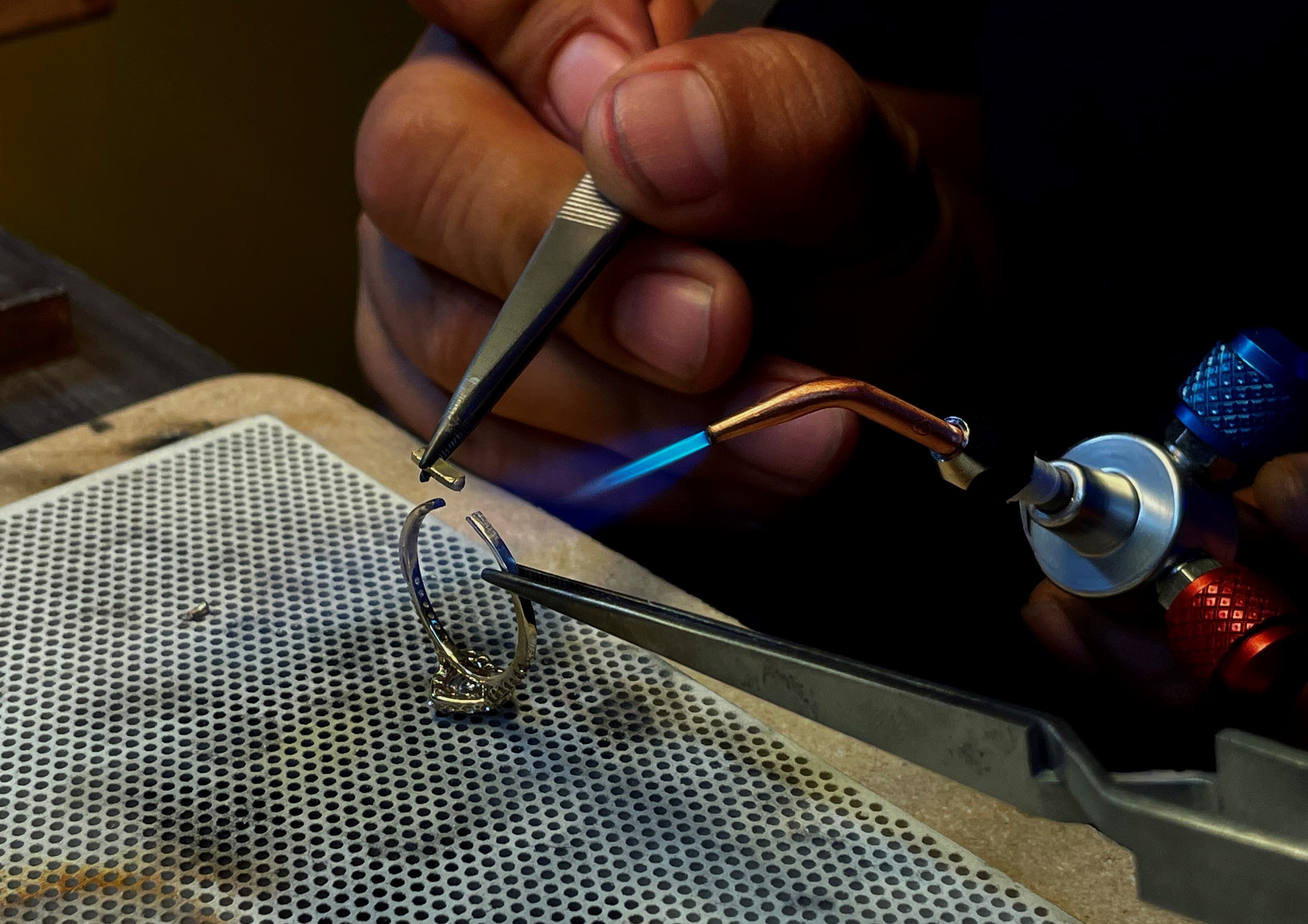 Man soldering a broken gold ring