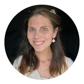 Eloise looks at the camera with a friendly smile as she writes in a notebook.