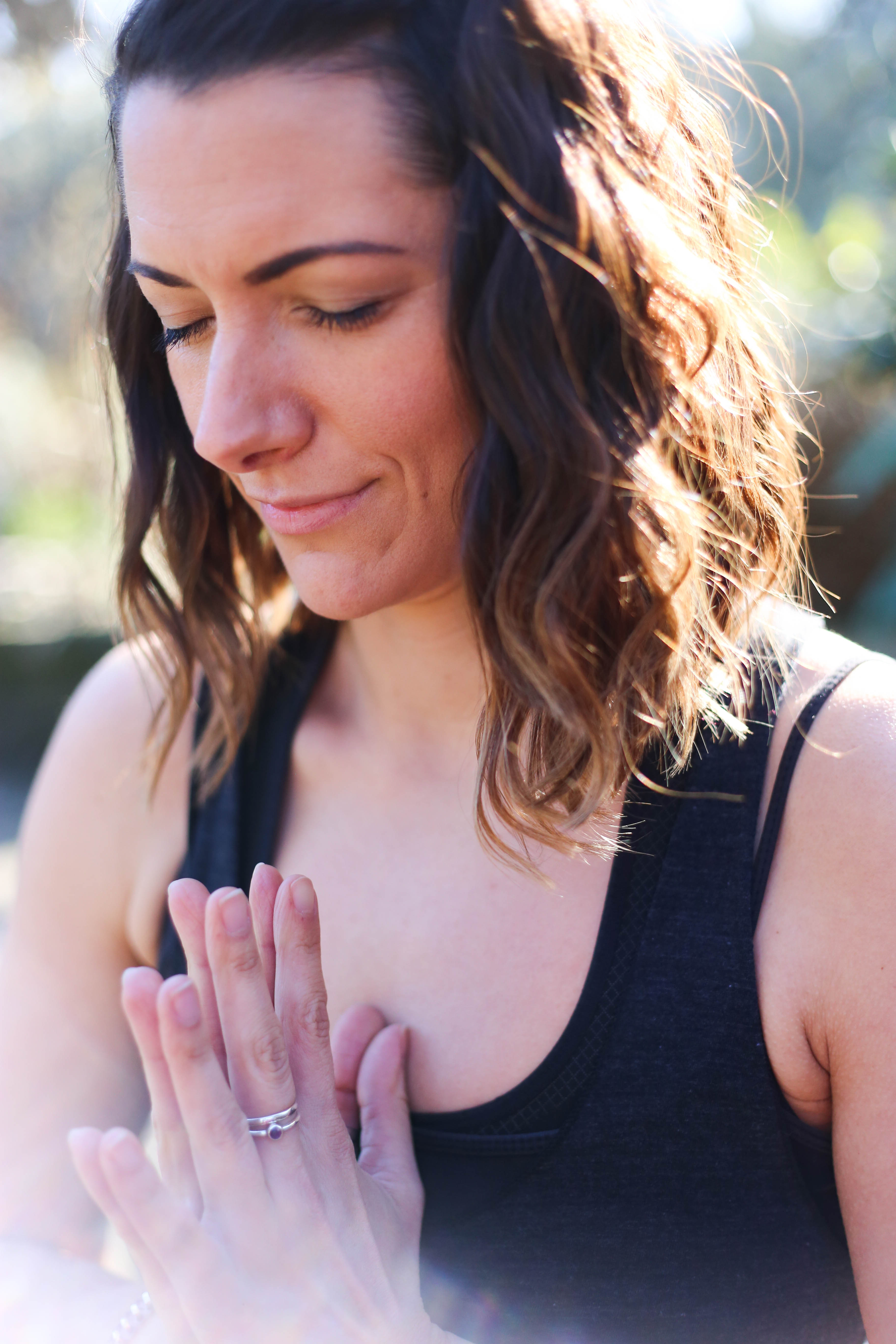 Aimee with her eyes closed and hands together at her heart centre.