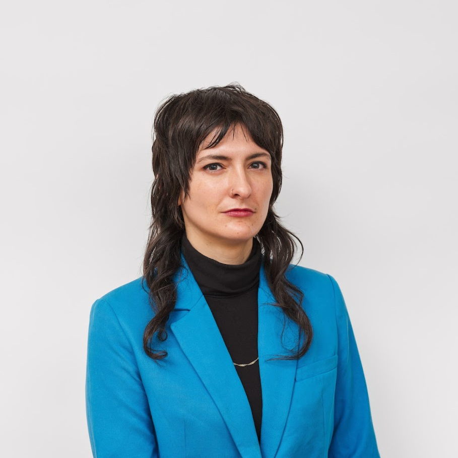 A person in a blue blazer in front of a gray background