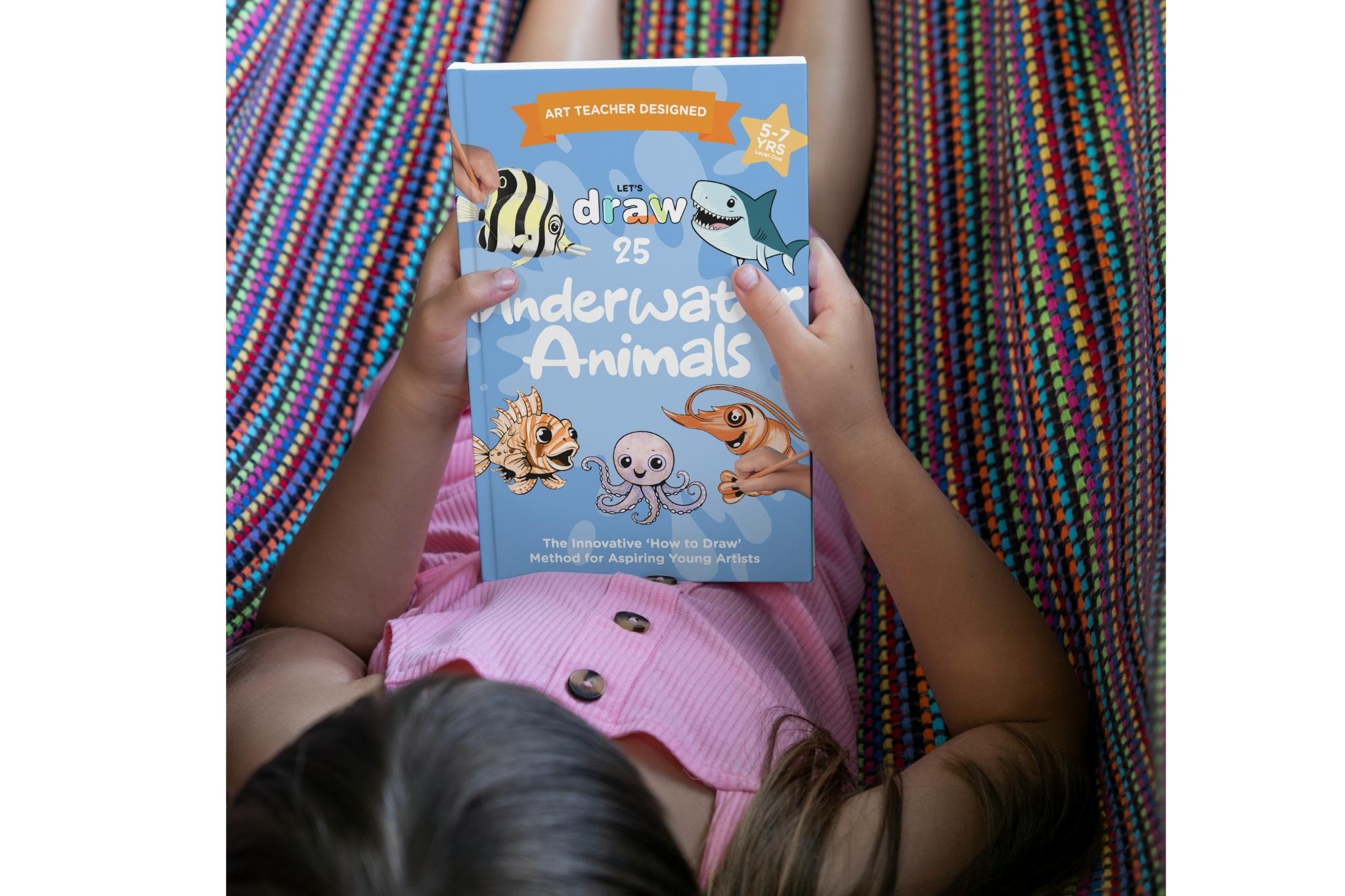 A girl holding the Let's draw: Undewater animals drawing book