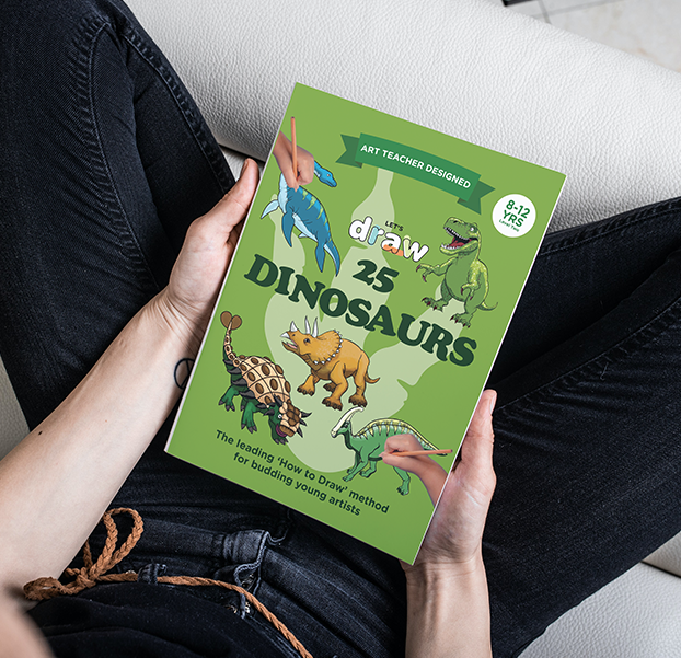 An older girl holding Let's draw: dinosaurs book level 2