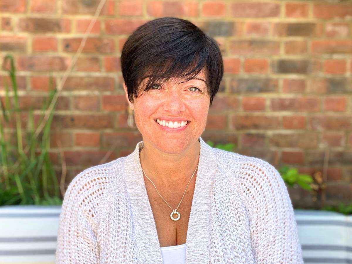 Amy-orsini-reiki-master-teacher-smiling at the camera in a beautiful garden