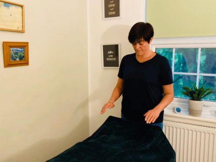 woman lying on a reiki bed relaxing receiving hands off reiki from a reiki master