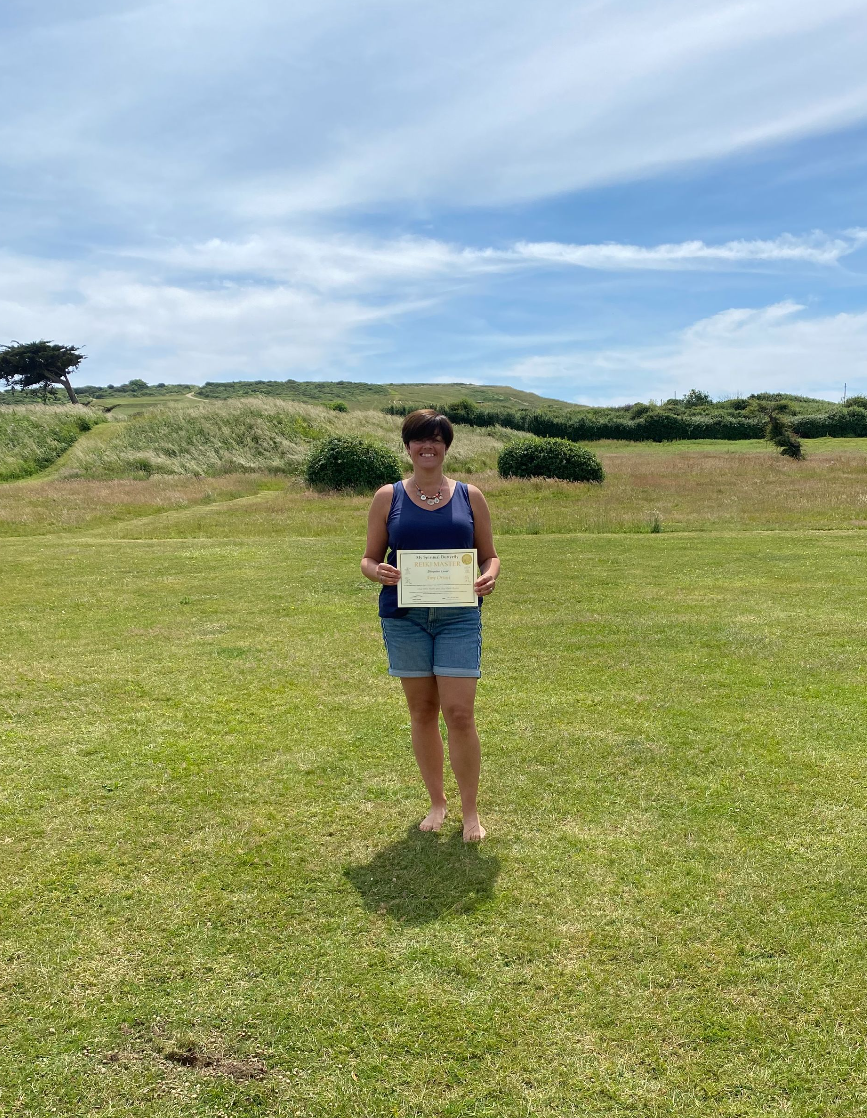 Reiki Master standing in a beautiful garden holding their Reiki Master certificate