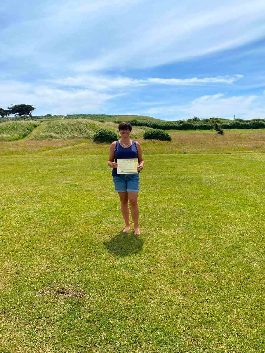 Reiki Master standing in a beautiful garden holding their Reiki Master certificate