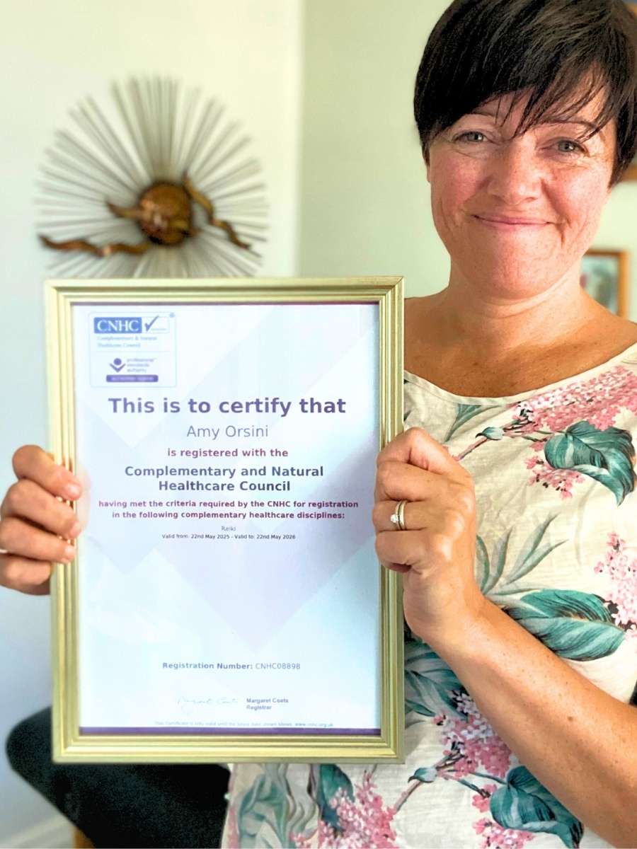 Our Reiki Master Amy in the Reiki treatment room holding her CNHC registration certificate