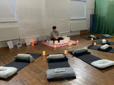 sound practitioner playing crystal singing bowls at a sound bath in Purley