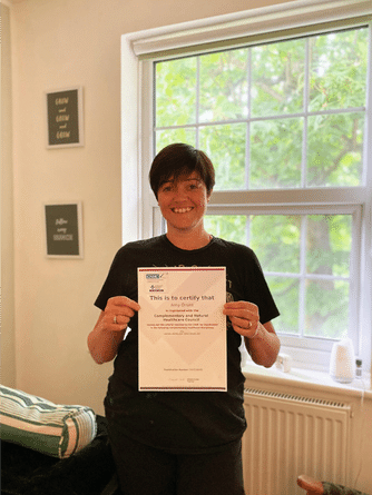 Our Reiki Master Amy in the Reiki treatment room holding her CNHC registration certificate