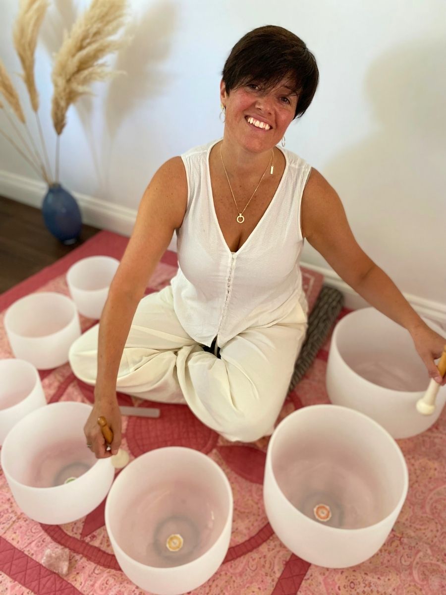 reiki master and sound bath practitioner playing crystal singing bowls