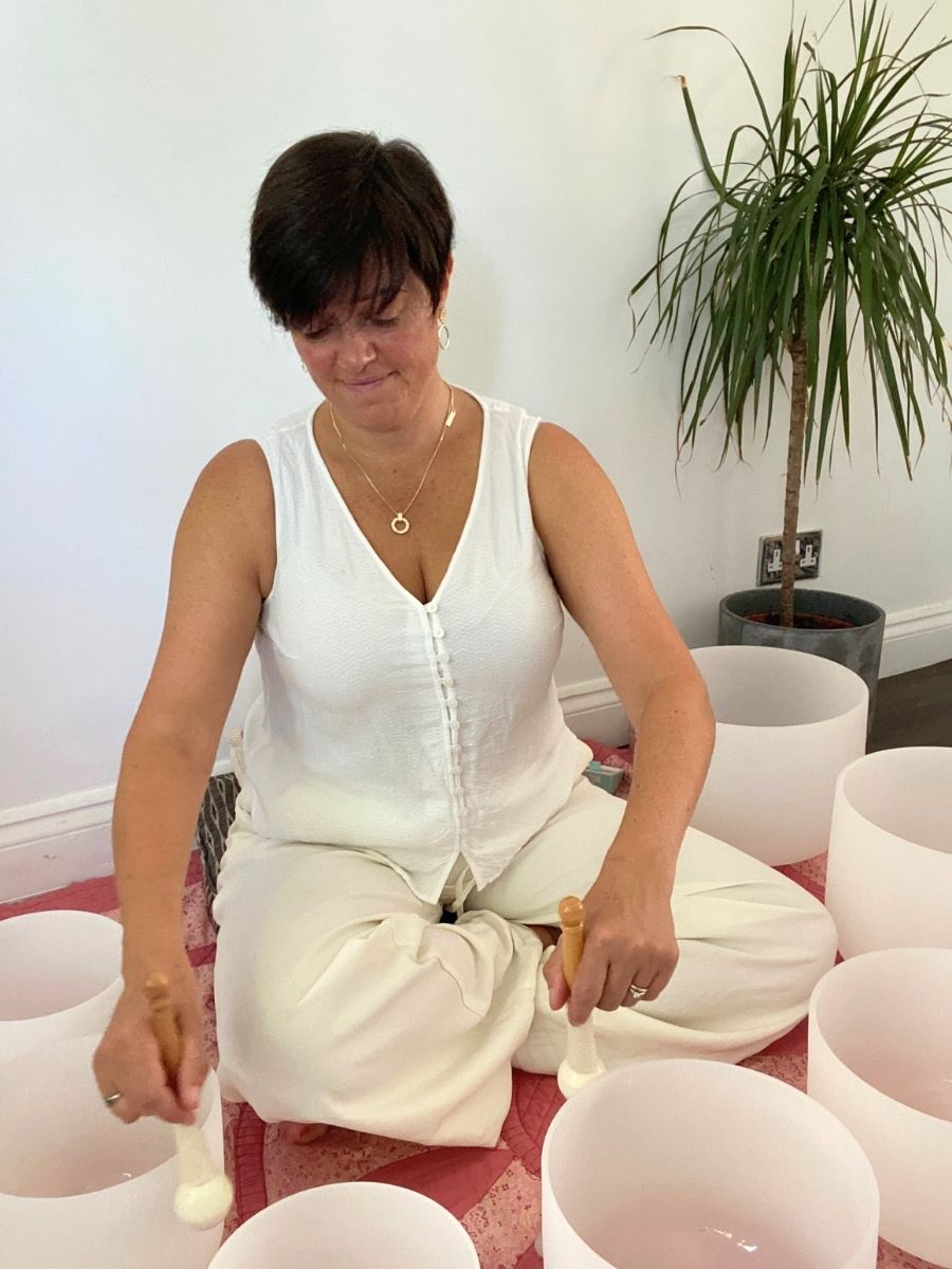 sound practitioner playing crystal singing bowls