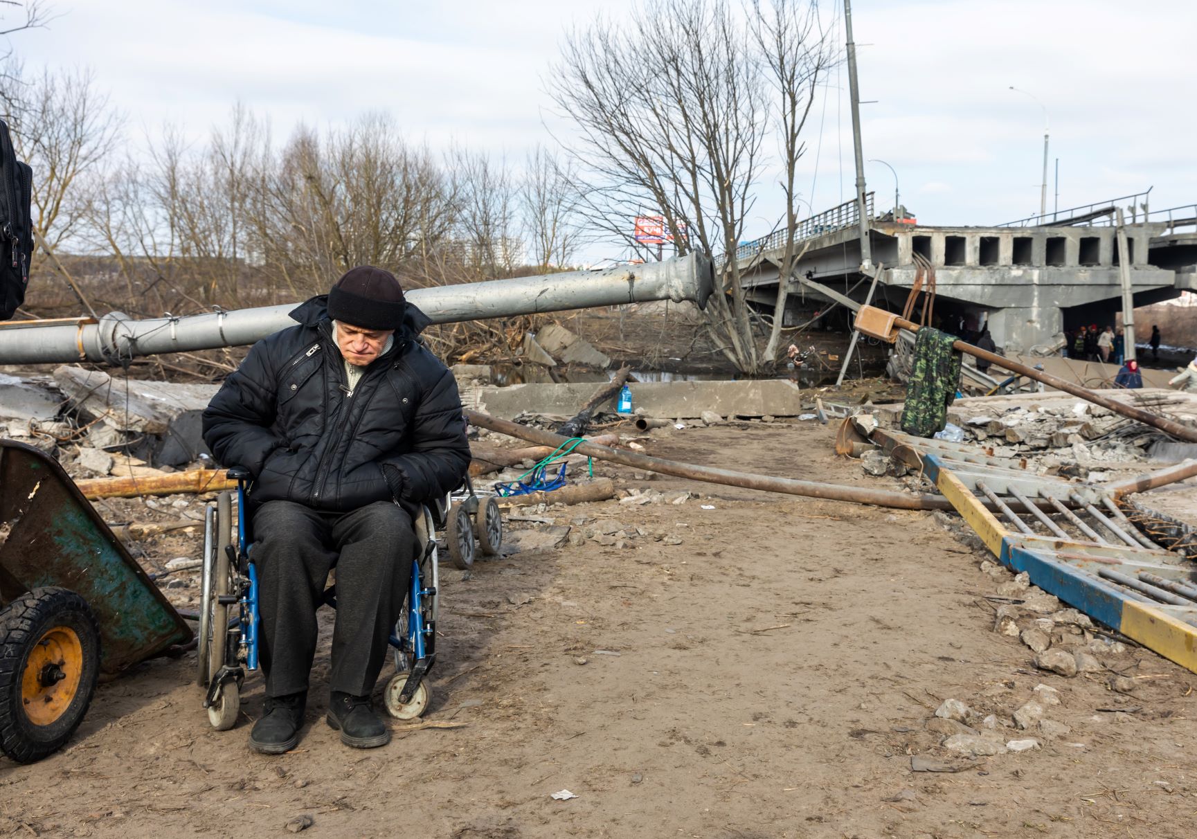 Man in wheelchair in front of bridge ruins
