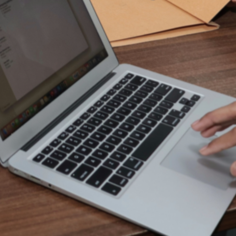 photo of laptop with a hand just coming into view touching the keyboard