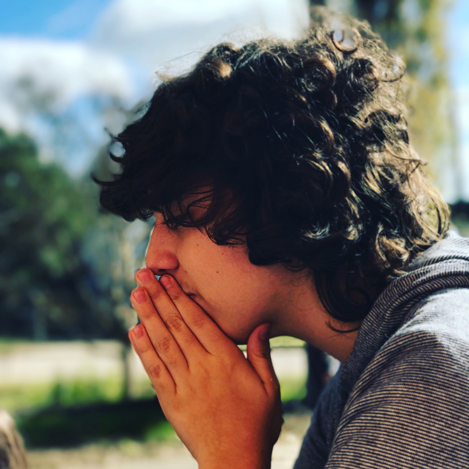 young man with his hands together next to his mouth looking anxious
