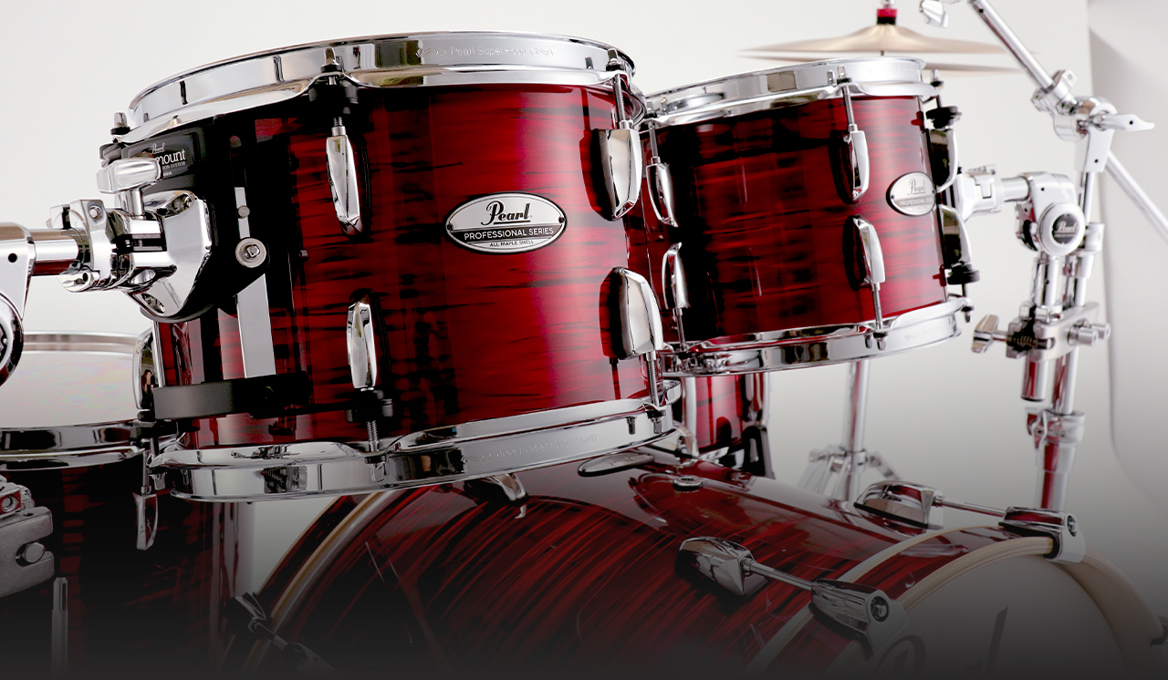 Close-up of a Pearl Professional Series drum kit with the new #808 Velvet Crimson finish. A deep red color with chrome hardware, showing mounted toms and part of the bass drum.