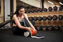 woman sitting in gym with injured ankle