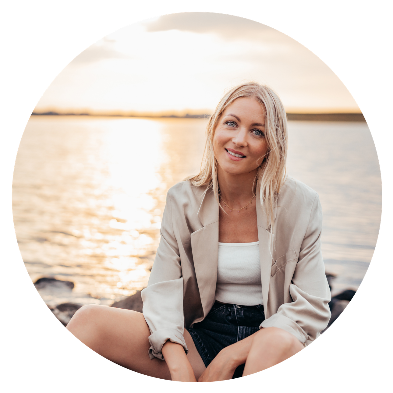 Picture of selfcare coach Luna Lova sitting on rocks by the water