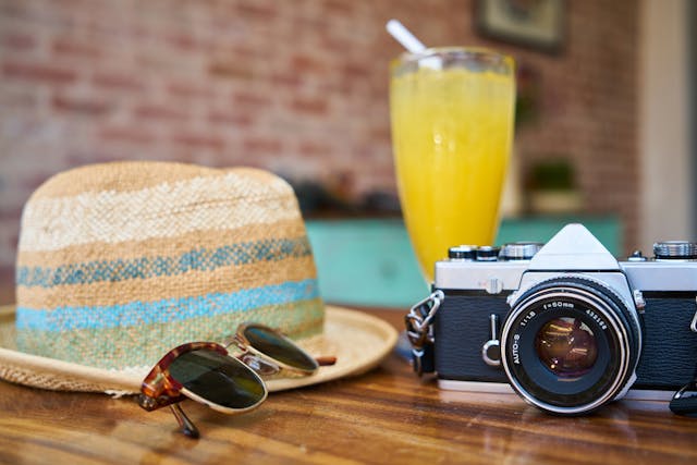 A large hat, sunglasses, a camera, and a beautiful drink all situated on a glossy wooden table, presented alongside the Near Me Discovery email sign up form, for your guide to hidden gems and local treasures of amazing places to find plus things to do near me and near you