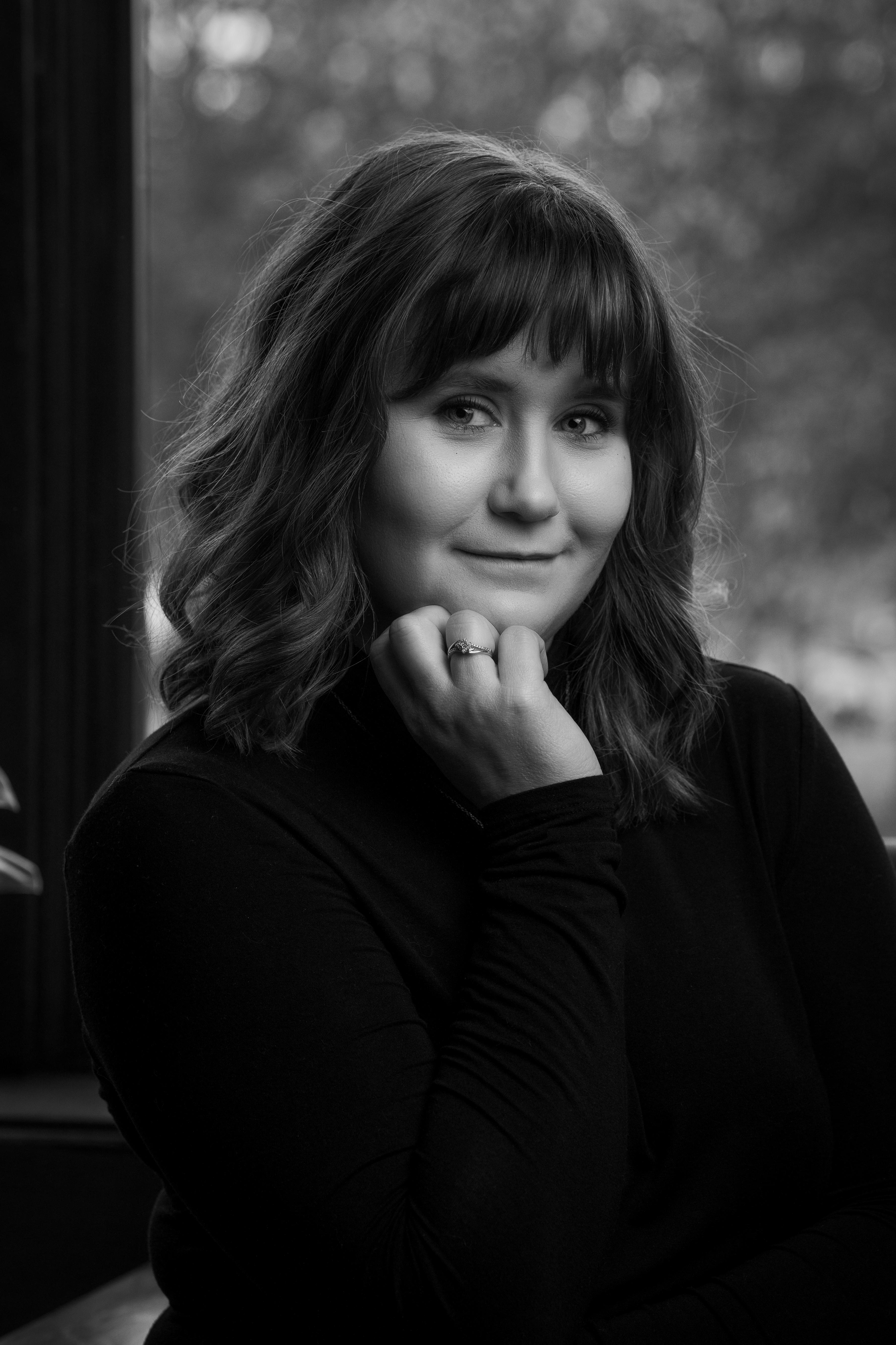 Image of author with her chin resting on her nuckles and a soft smile on her face.