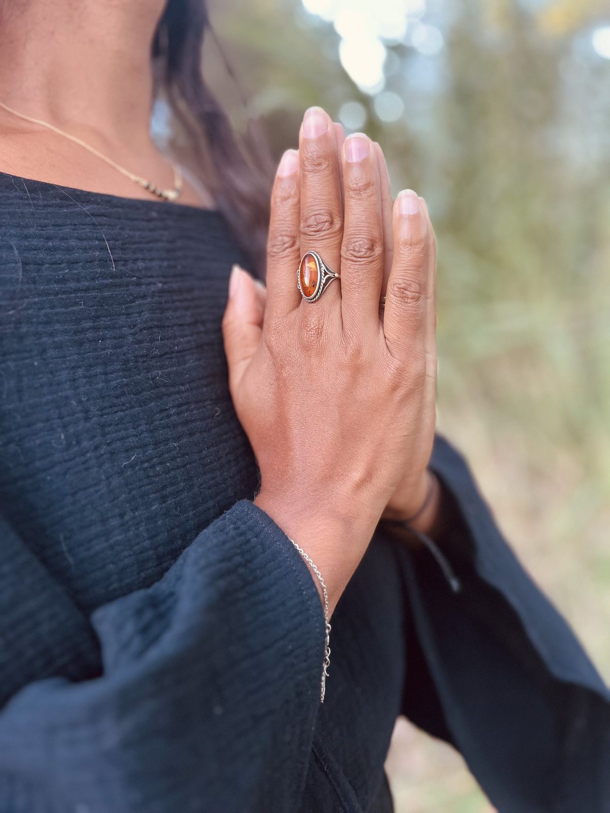 Les mains de Davina jointes devant le cœur, avec une bague d’ambre