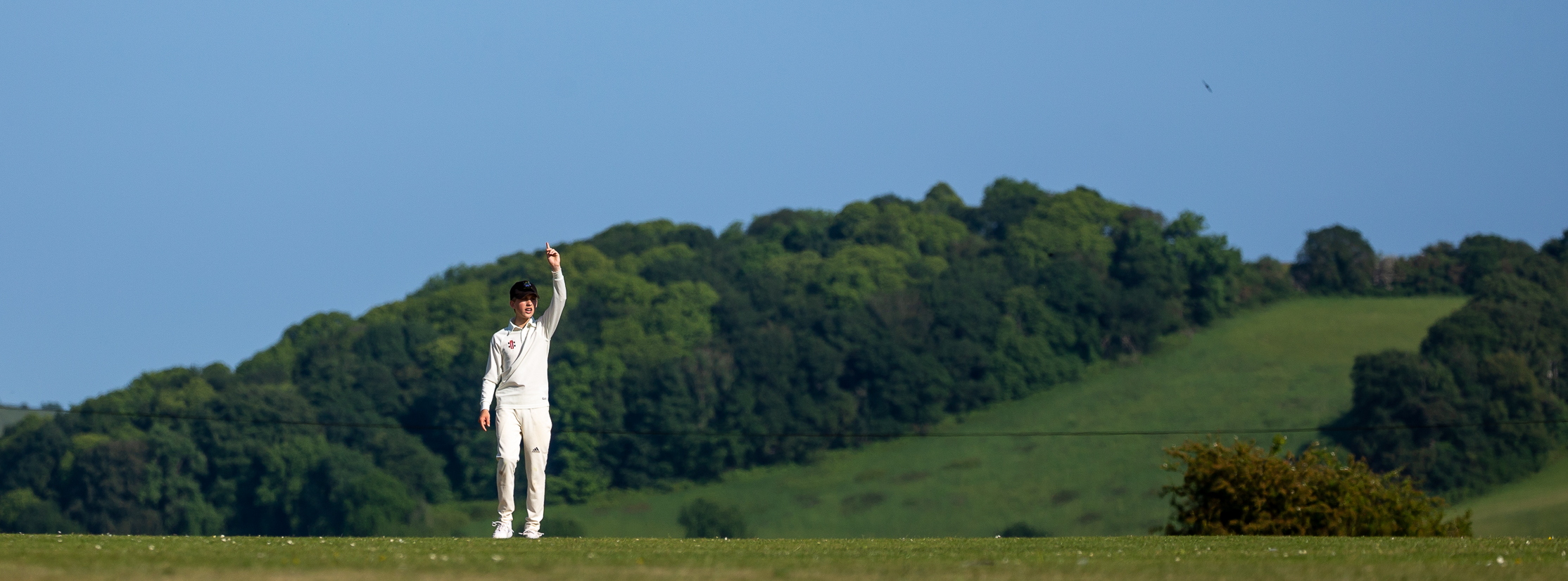 Fielder pointing his finger to the sky in from of rolling hills