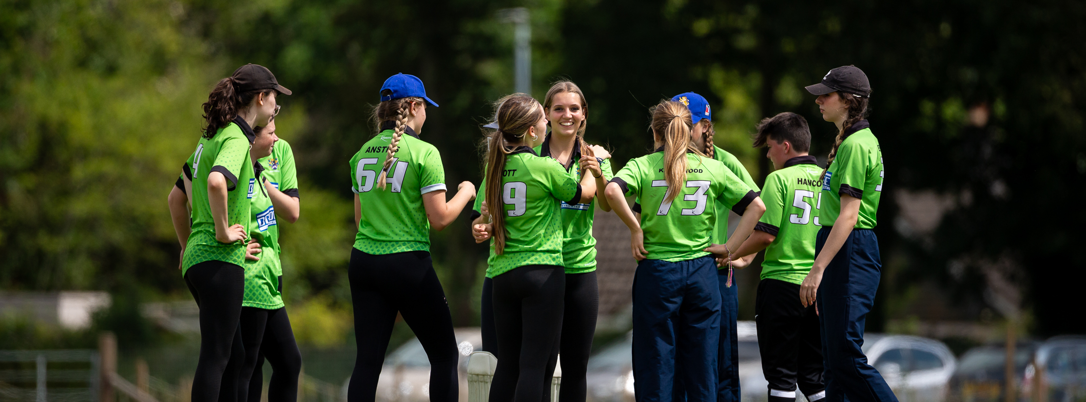 Women's cricket players celebrating a wicket