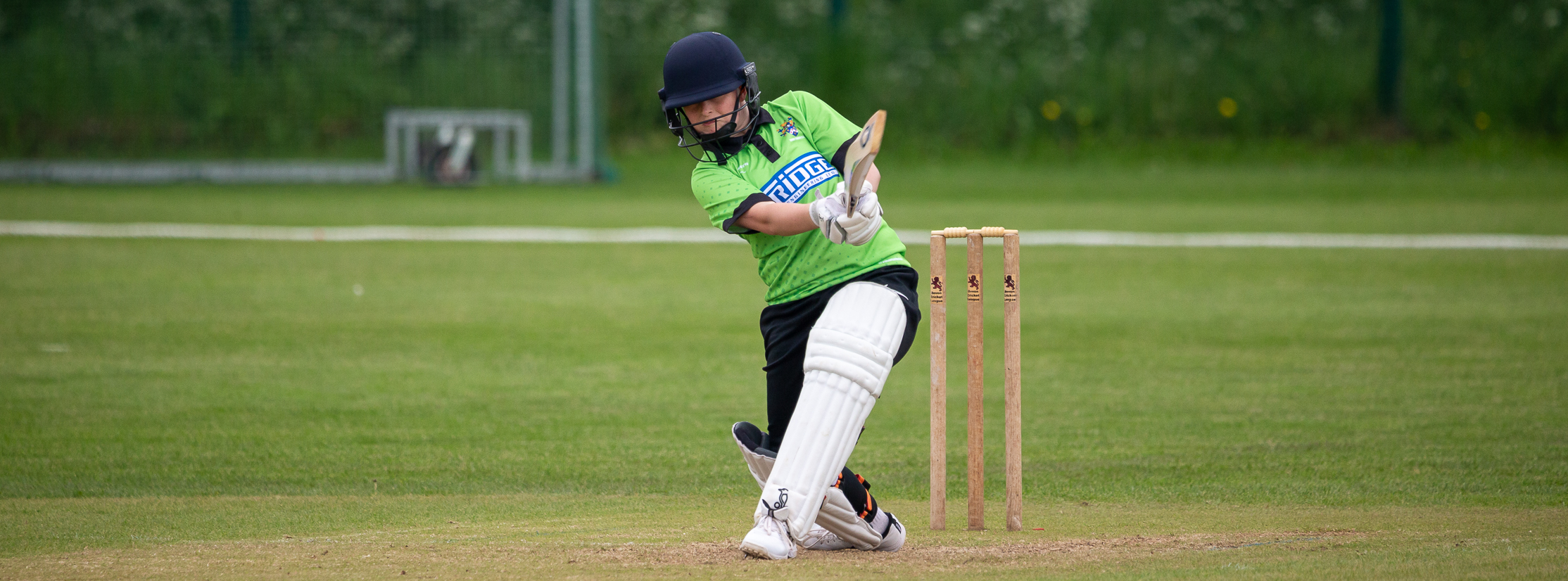 Junior girls batter hitting a cover drive