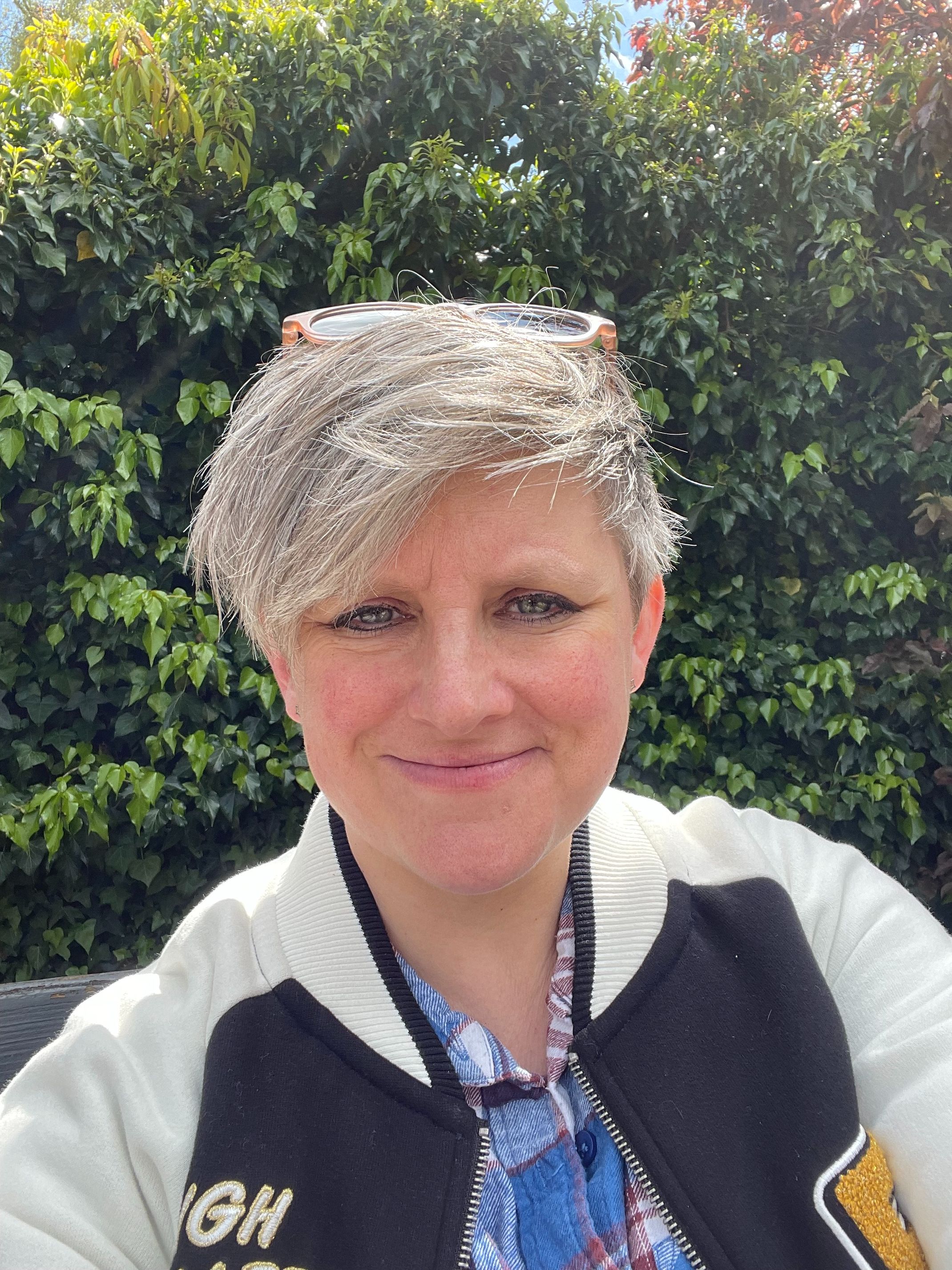 Woman with short blonde/grey hair smiling at camera.