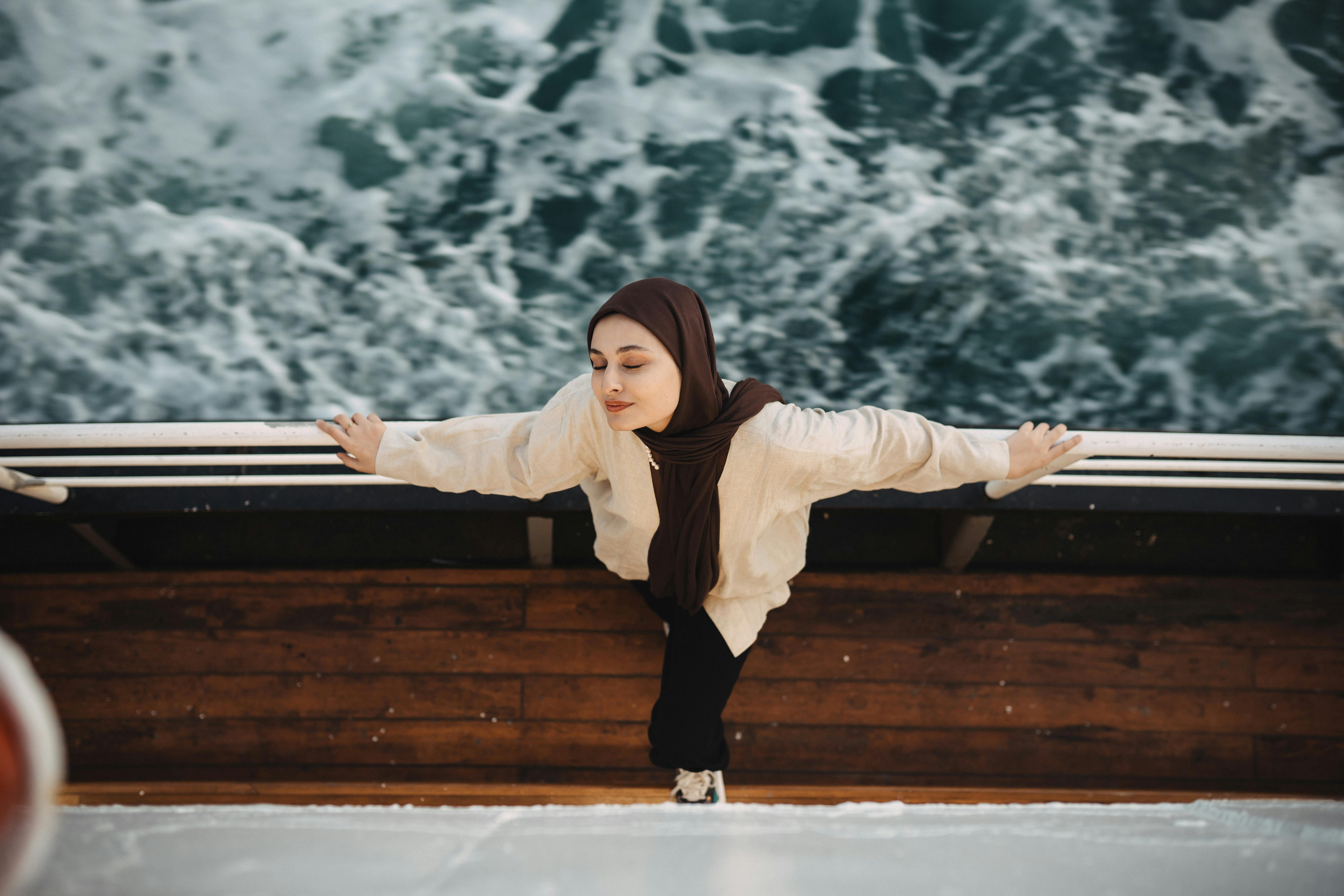 The photograph is taken from above, a girl is standing on the edge of a ship en is looking up. You see the ship and a part of the ocean