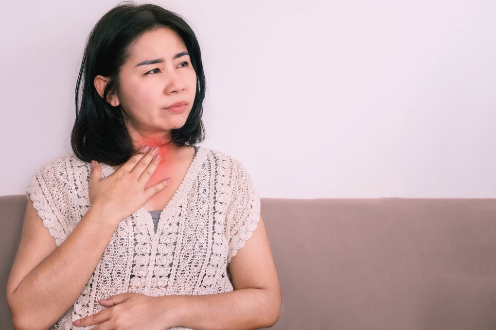 Frau hält sich den Hals mit sichtbarer Rötung, zeigt mögliche Symptome von Entzündungen, relevant für das Thema chronische Entzündungen in den Wechseljahren und ihre gesundheitlichen Auswirkungen.