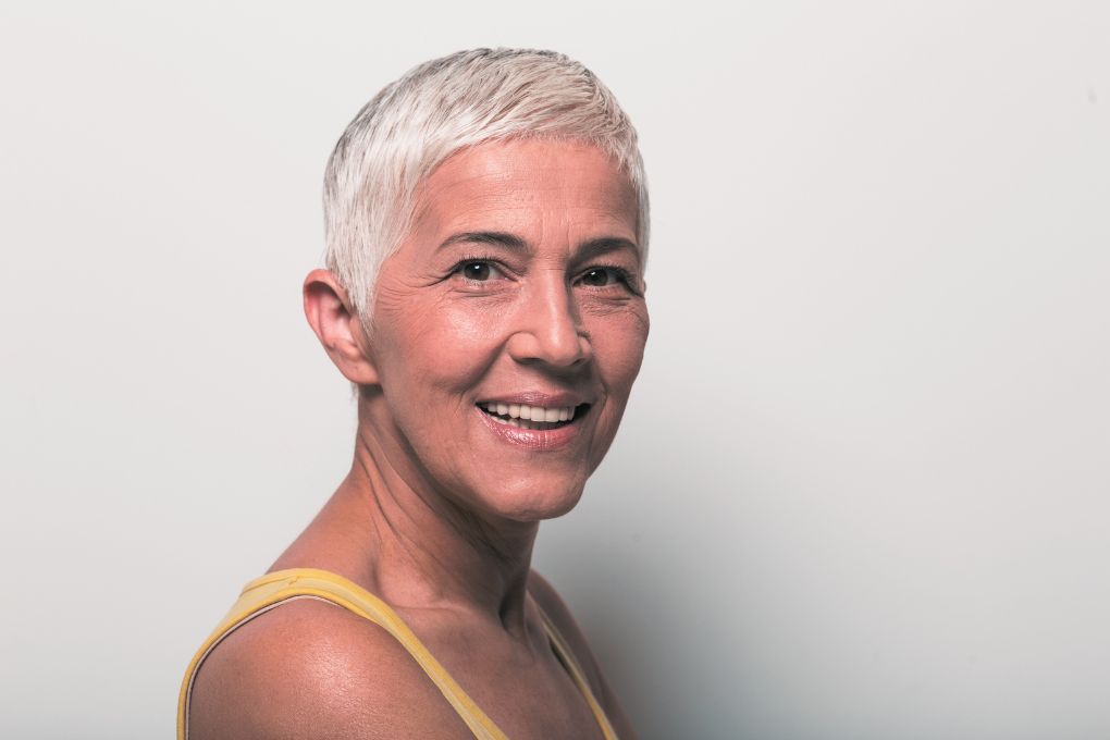 Porträt einer selbstbewussten Frau mit kurzen grauen Haaren und einem warmen Lächeln – Symbol für positive Ausstrahlung, Selbstakzeptanz und Lebensfreude in den Wechseljahren