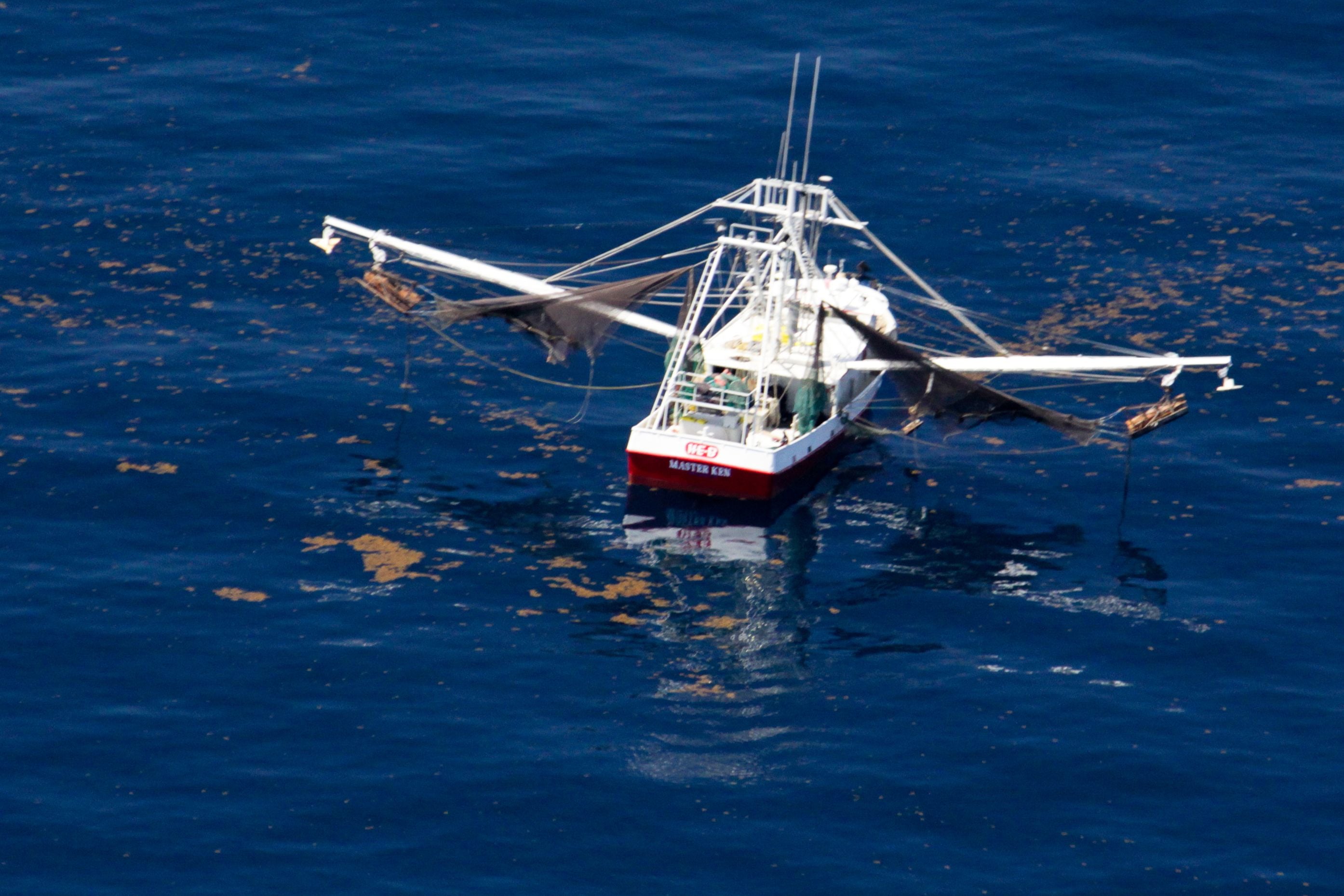 High-angle shot of a commercial fishing boat with outriggers extended on a calm ocean