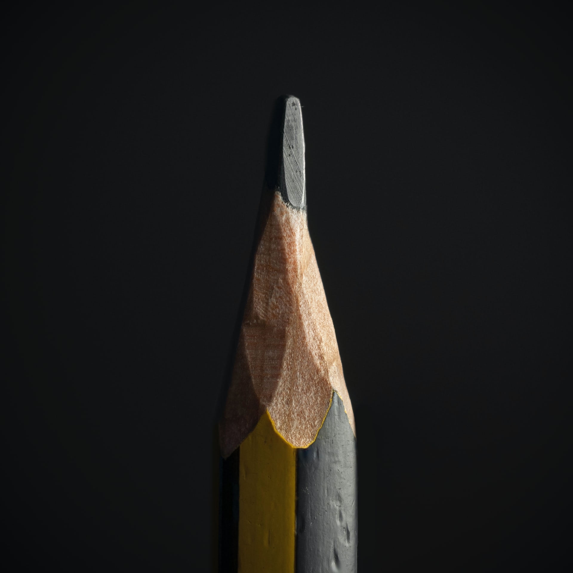 A close up picture of the tip of a sharpened pencil on a dark background